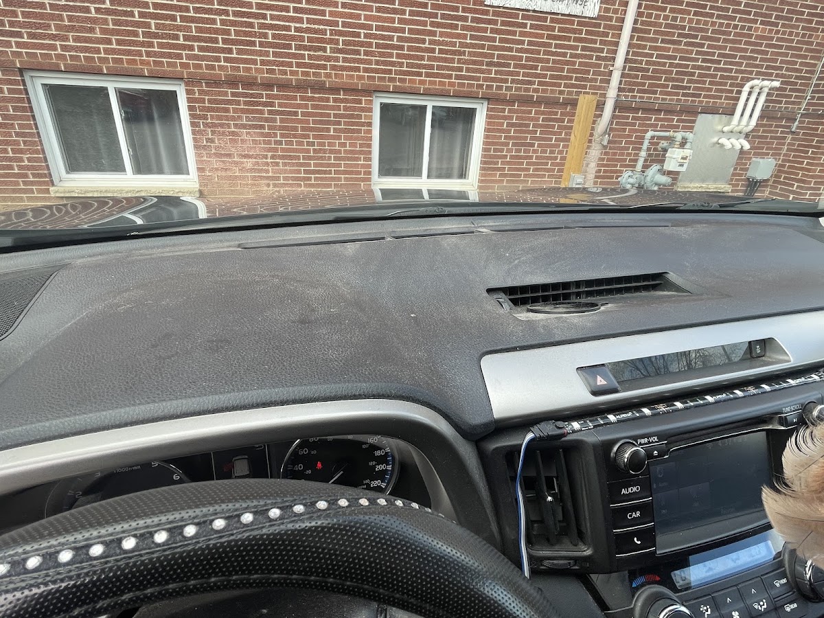 Dust-covered dashboard before detailing — vents and console included.